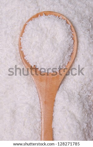 Shredded coconut in a wood spoon.
