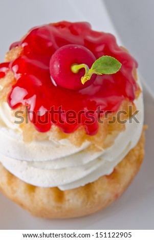 Traditional savarine with lots of whipped cream an a cherry on top.