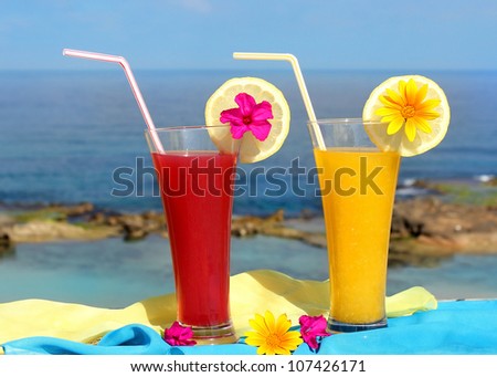 red and yellow fruit cocktails on the background of beautiful sea landscape