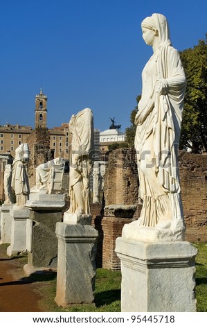 Ancient Roman statues stand on pedestals in the open air in Rome
