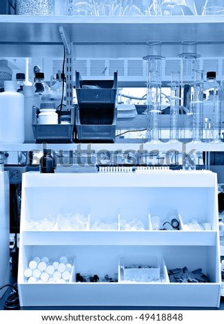 Typical chemistry lab bench, with many supplies and reagents on the shelves - blue monochrome