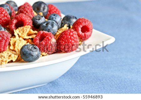Bowl of berry cereal on blue tablecloth. Shallow depth of field.