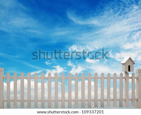 white fence with bird house and blue sky