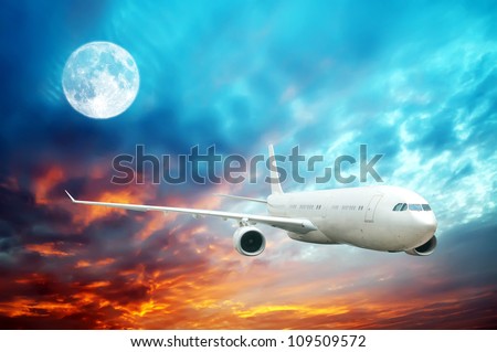 A plane flying high in the nighttime sky with an illuminated moon