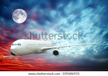 A plane flying high in the nighttime sky with an illuminated moon