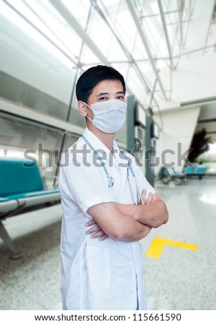 Asian male doctor with face mask portrait standing inside hospital building