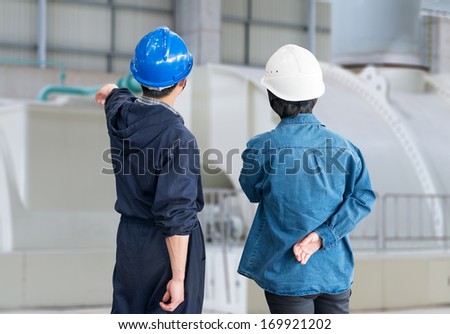 A team of construction workers with helmets at work place in a factory