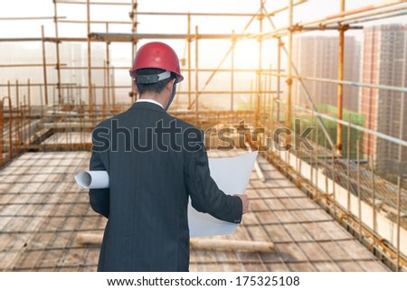 Rear view of architect looking comparing housing project with building