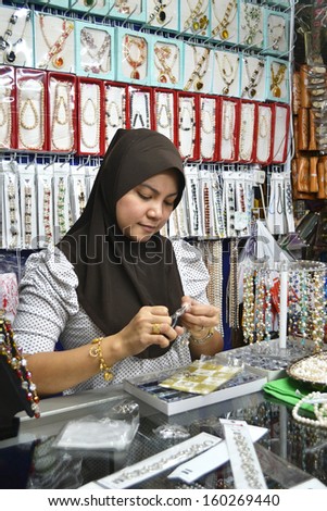 KOTA KINABALU, SABAH, MALAYSIA - FEB 2: Muslim woman repair bracelet for sale on Feb 2, 2011 at Muslim Street in Kota Kinabalu, SABAH.