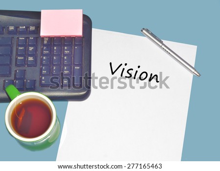Keyboard with text VISION on table with tea, calculator and pen