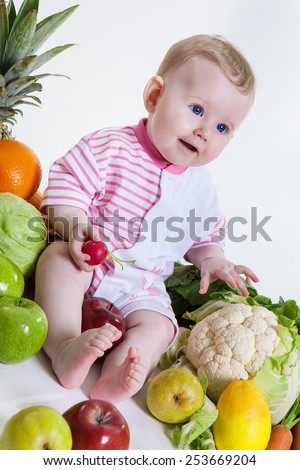 Cute baby  sitting with fruits and vegetables and hold an apple isolated on white background. Concept: healthy vitamin vegetable food diet make baby strong and happy