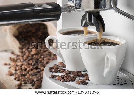 coffee machine makes two coffee with coffee beans on background