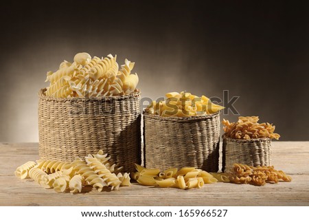 straw baskets with variety of uncooked pasta on wooden table