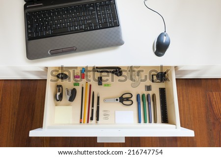 desk with notebook and open drawer with office tools