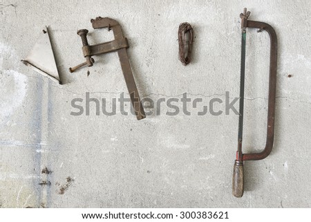 old hacksaw and clamp  hanging on garage wall