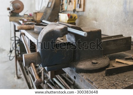 old bench vise with threaded bar and old work tools in home garage