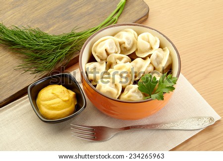 Russian dumplings - pelmeni, in orange bowl with mustard