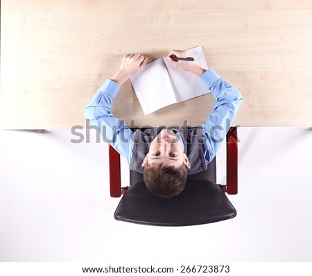Boy sitting in a chair at the office table. Top view