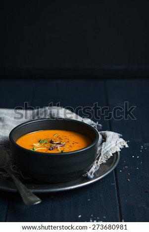 Creamy tomato soup with noodles against black wooden background
