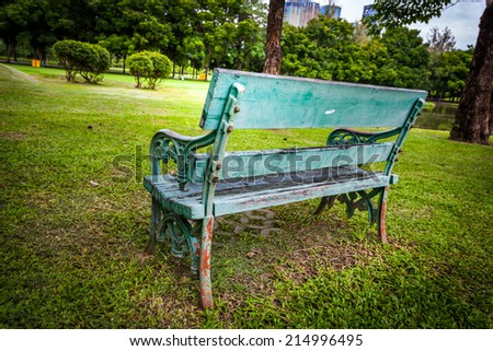 Green bench, chair, stool beside walkway in the public park,