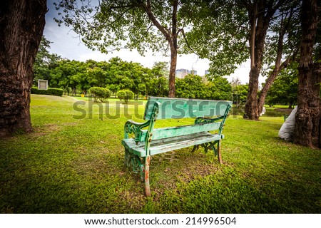 Green bench, chair, stool beside walkway in the public park,