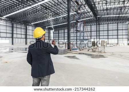worker or engineer with yellow helmet for workers security holding radio communication in a construction site warehouse