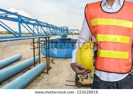 engineering man with yellow safety helmet standing in front of water treatment plant
