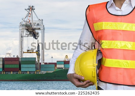 engineer with Container Cargo freight ship with working crane loading bridge in shipyard with Blue Sky at Logistic Import Export Zone background