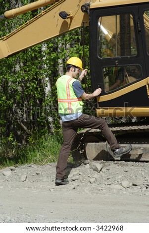 A construction worker prepares to climb into a utility excavator.