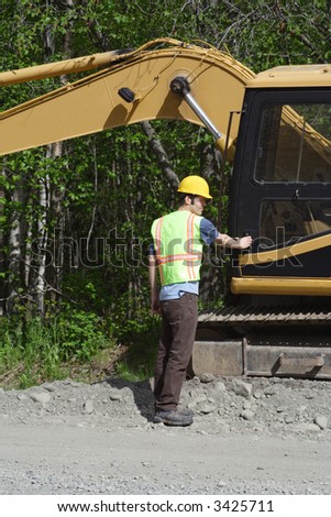A construction worker prepares to climb into a utility excavator.