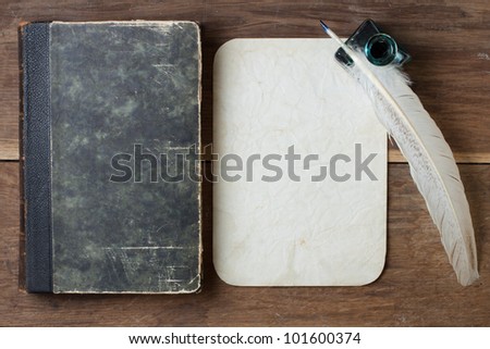 Book cover, quill and inkwell, old grunge paper on wood background