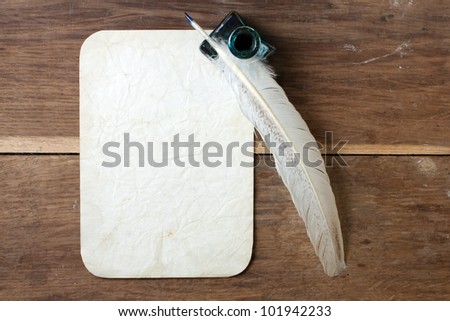 Quill and inkwell, old grunge paper on wood background