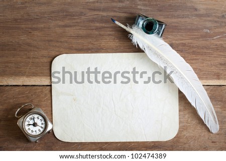 Quill and inkwell, old grunge paper, vintage clock on wood