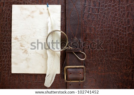 Vintage crocodile leather textured background with magnifying glass, quill and paper blank