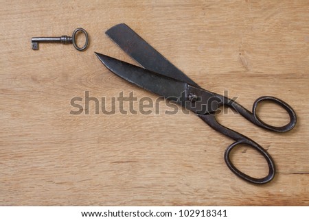 Old scissors and key on wood