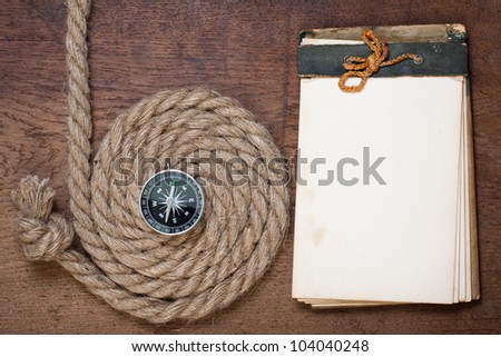 Old notebook, compass, rope on the old wood background