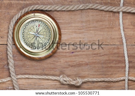 Old compass and rope frame on wooden background