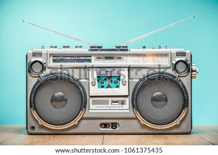 Retro outdated portable stereo boombox radio receiver with cassette recorder from circa late 70s front aquamarine wall background. Listening music concept. Vintage old style filtered photo