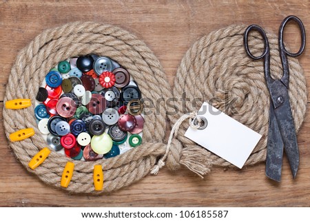 Color buttons in rope frame, old scissors, price tag  on wooden background
