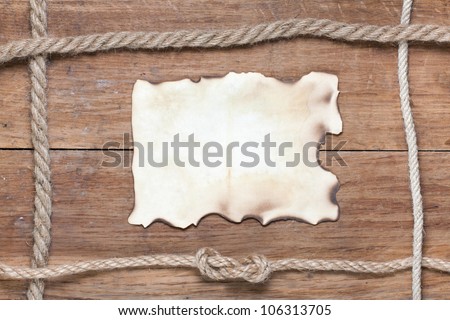Old burnt paper on wood with rope frame background