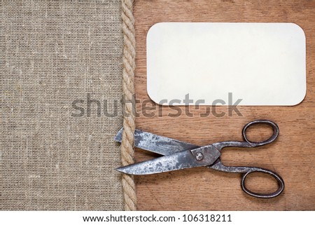 Old scissors on canvas and wood textured background with paper frame
