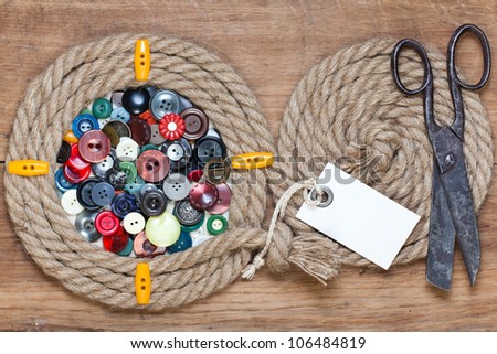 Color buttons in rope frame, old scissors, price tag  on wooden background