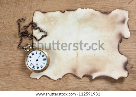 Burnt paper and antique pocket watch on wood