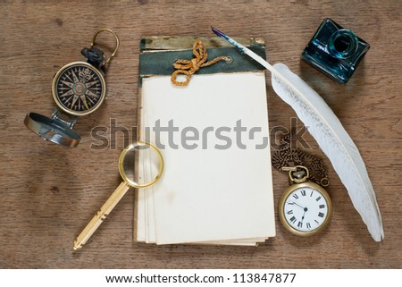 Old notebook, compass, pocket watch, quill and inkwell, magnifying glass on wooden texture