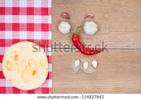 Red and white kitchen textile, cheese, chili pepper, garlic, bay leaf, on oak wood board background