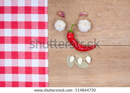 Red and white kitchen textile, chili pepper, garlic, bay leaf on oak wood board background