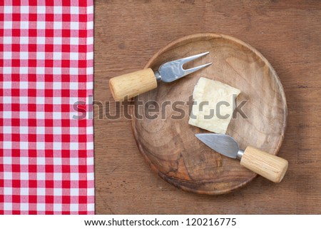 Tablecloth, parmesan cheese and knife in wooden plate on oak board