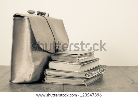 Vintage leather bag, old books on grunge wood