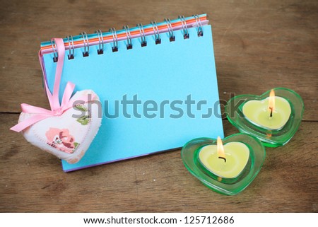 Valentine heart, note paper blank, burning candles on wooden table background