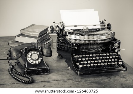 Vintage typewriter, telephone, old books on table desaturated photo